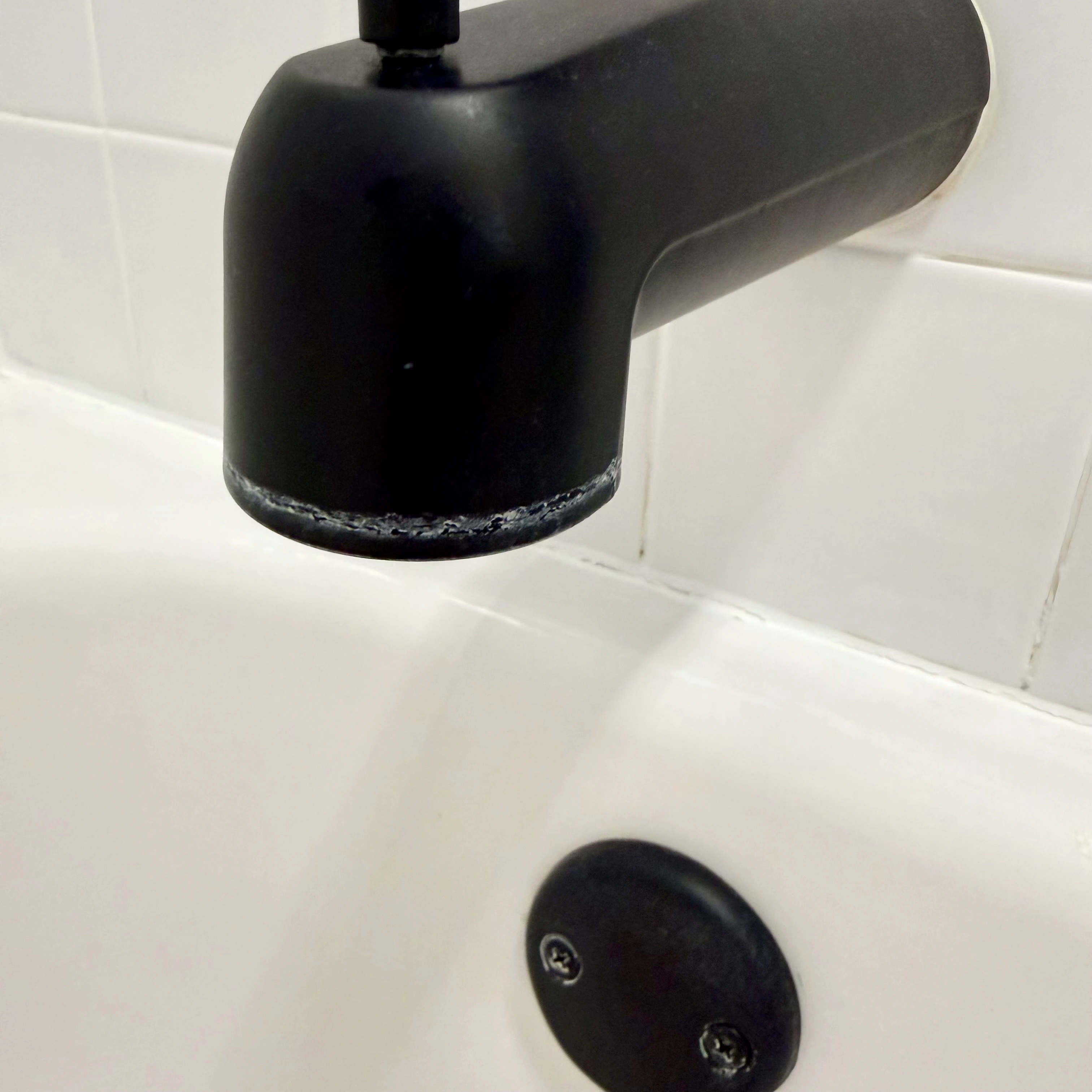 White hard-water spots and buildup on bathtub hardware